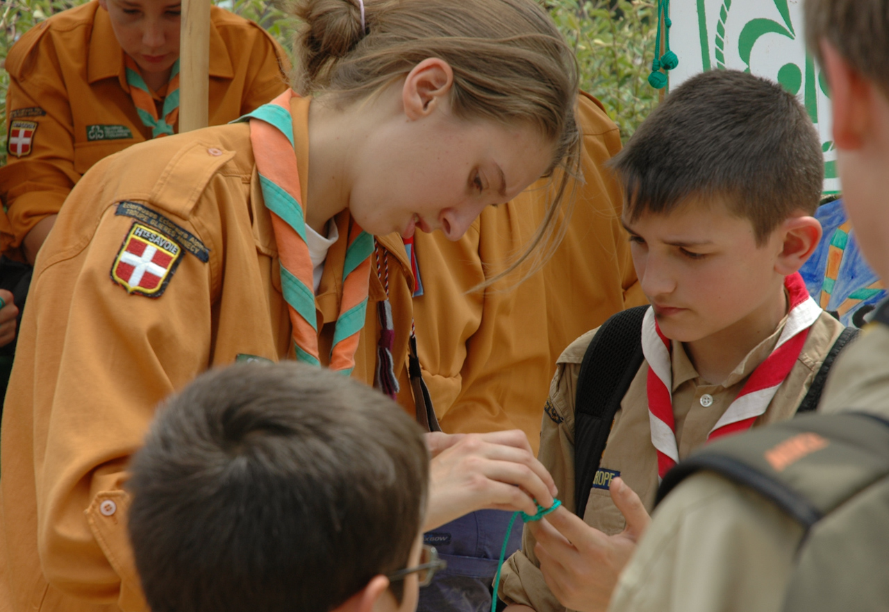 Une cheftaine FEE apprend à un scout AGSE à réaliser une bague de foulard
